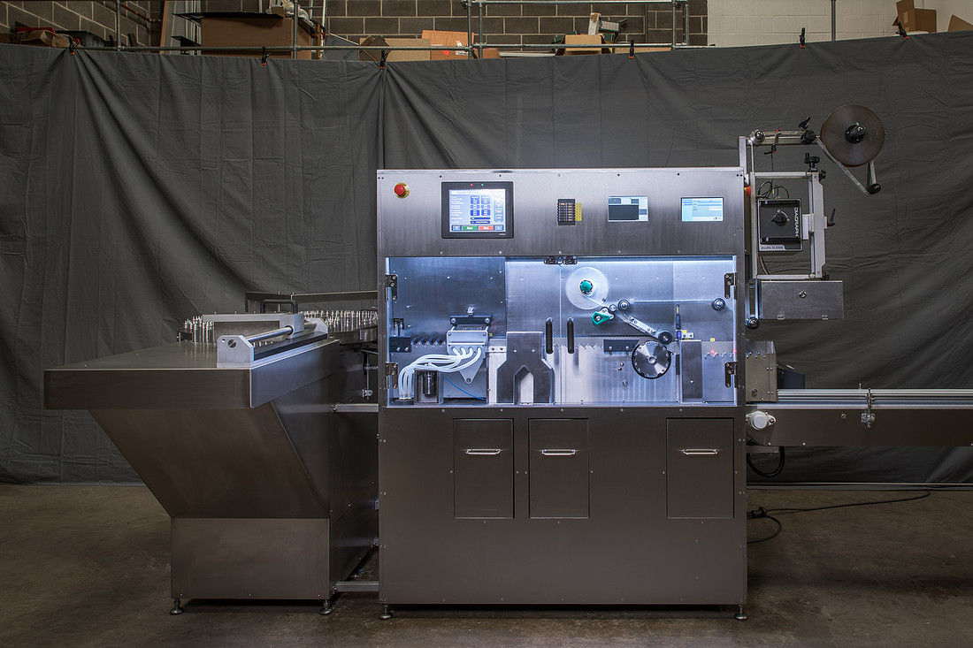 A large stainless steel automatic labelling machine photographed full width in the workshop.