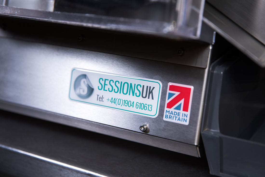 A SESSIONSUK badge on the stainless steel frame of a machine, showing the phone number beside a Union flag "Made in Britain" mark.